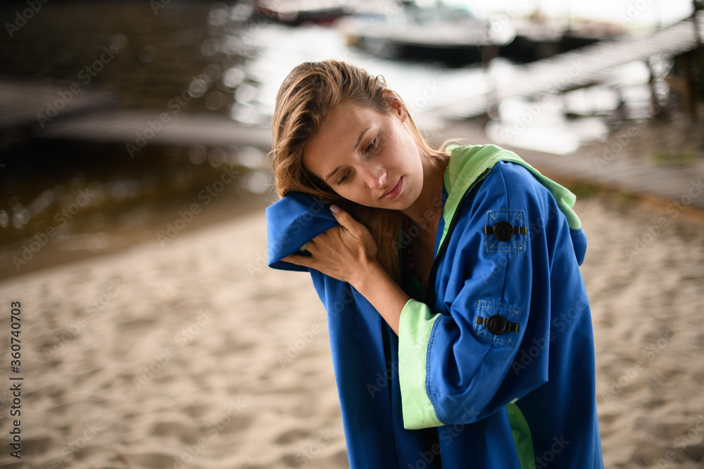 Naklejka premium young woman wipe her hair with towel on background of sandy river pier