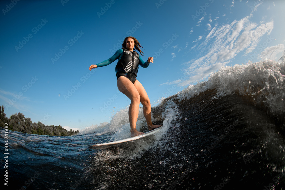 Young brown-haired woman on board riding wave