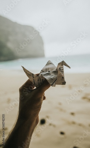 Person holding a cute paper crane in the beach of Nusa Penida island in Bali, Indonesia photo