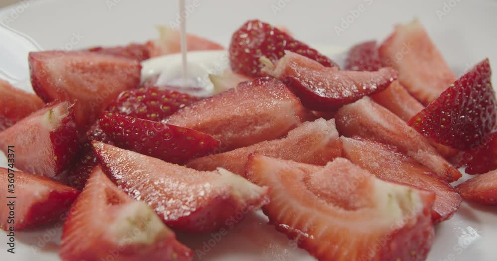 Pouring yogurt on freshly cut strawberries on a white background. Fresh strawberries poured over yogurt, slow motion. Pouring yogurt on freshly cut strawberries on a white background. Fresh strawberries poured over yogurt, slow motion.