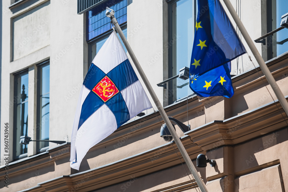 Waving flag of Finland and European Union flag hanging on the finnish institutions and administrative building in Helsinki, Uusimaa region