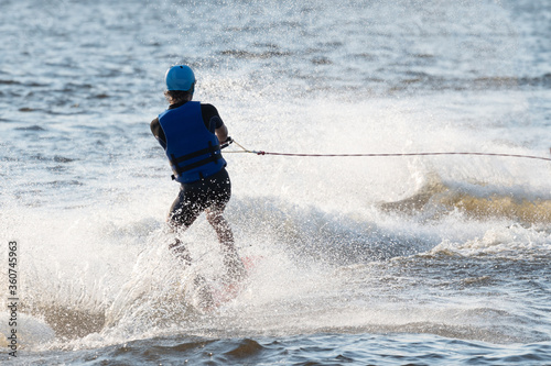 Unrecognizable man trying wake surfing with multiple splashes and waves © ilyaska