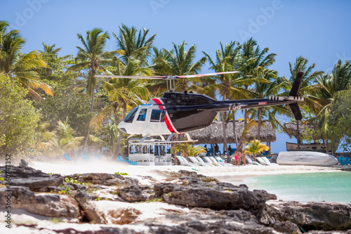 Blue helicopter landing on tropical caribbean beach during private excursion in Dominican republic to Saona island