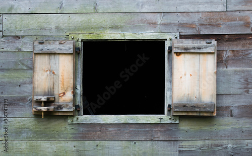 exterior wooden wall of a vintage colonial New England cabin with an open shutter window and copy space