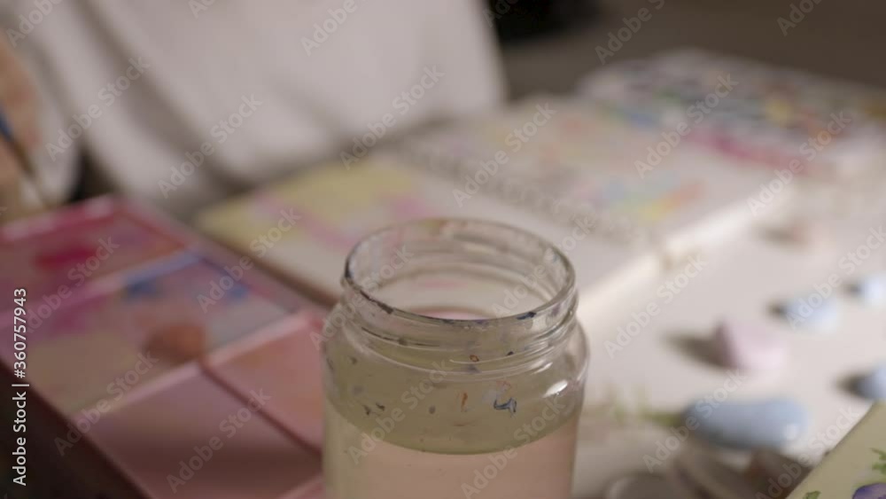 dipping paintbrush in water jar to clean