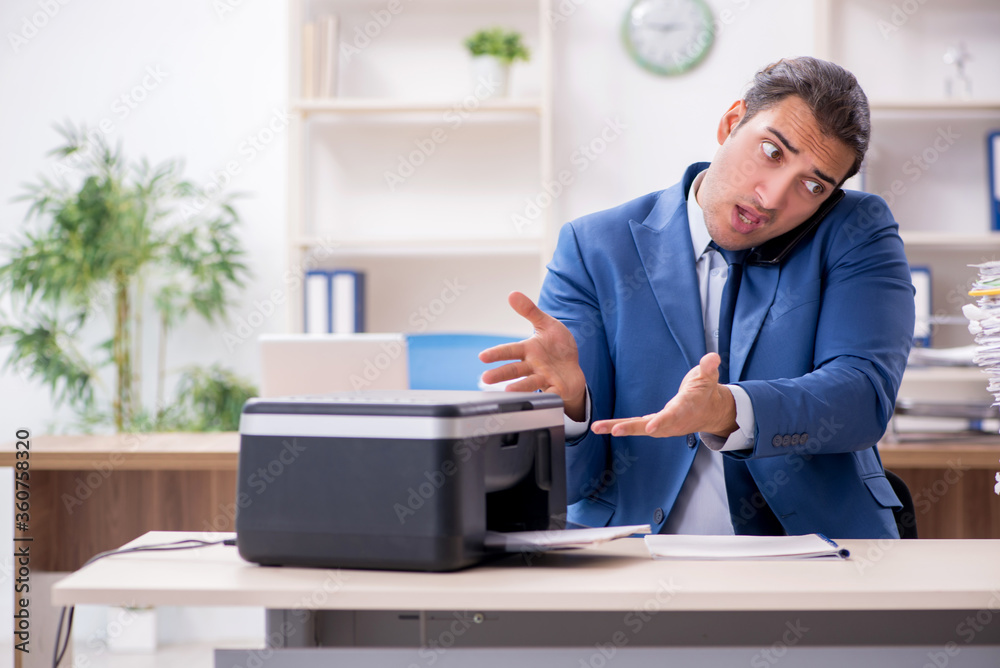 Young male employee making copies at copying machine