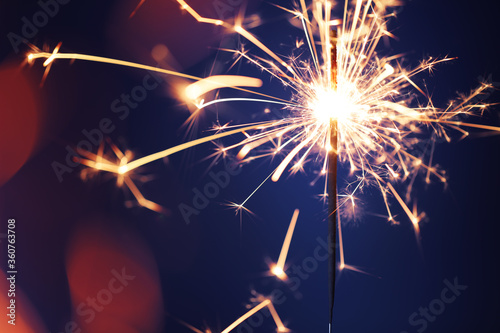 Close up of burning sparkler firework with lots of hot glowing embers exploding. For New Years or 4th of July celebration.