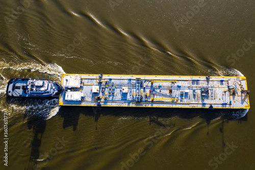 Tug and oil barge passing on the muddy hudson river as seen from above.