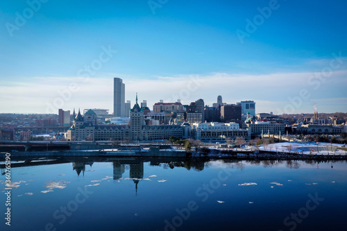 Albany NY skyline on a winter day seen from across the calm and reflective hudson river with ice floating in the river