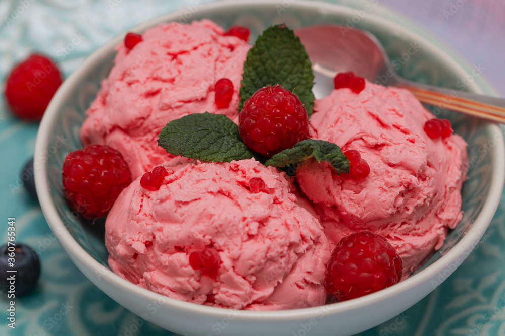 three balls of raspberry ice cream with three leaves of mint and berries in a bol very close-up.
three balls of raspberry ice cream with three leaves of mint and berries in a bol very close-up.