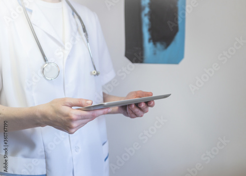Medical doctor or physician consulting patient's health online using internet mobile digital tablet in clinic or hospital office for professional emergency healthcare assistance service concept. photo