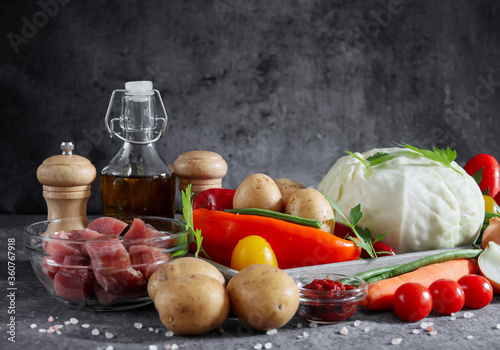 Fototapeta Naklejka Na Ścianę i Meble -  vegetables with meat, salt, olive oil on a stone background, closeup side view.
