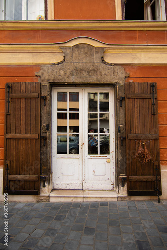 Beautiful elegant white door in a building with orange walls. Wooden shutters. Historical heritage in the European city of Budapest, Hungary.