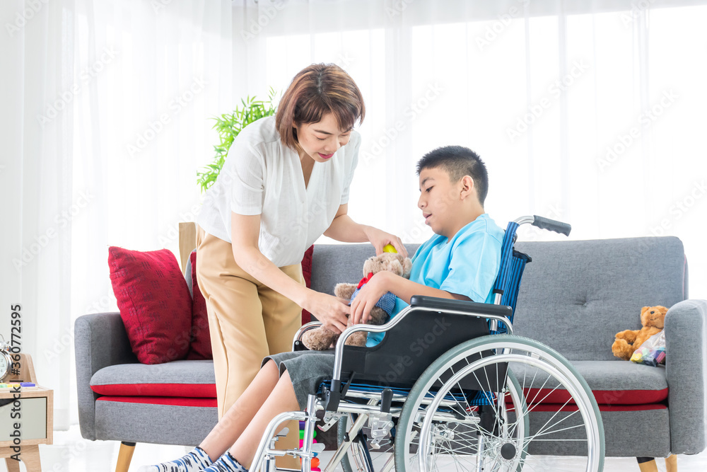 asian woman playing with disabled child on wheelchair in living room asian woman playing with disabled child on wheelchair in living room