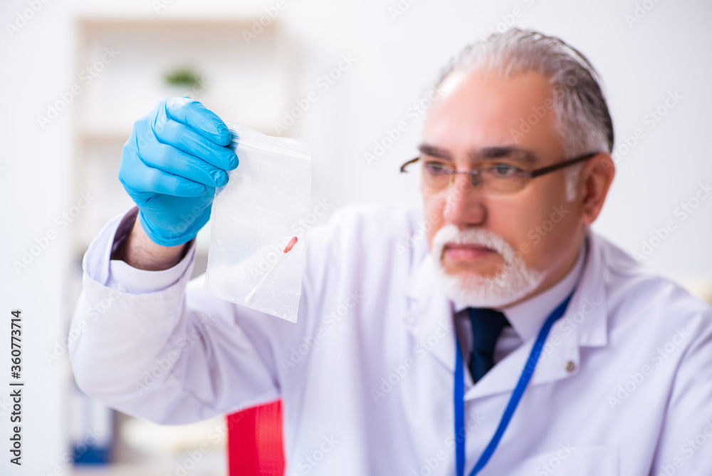 Old male expert criminologist working in the lab for evidence Old male expert criminologist working in the lab for evidence
