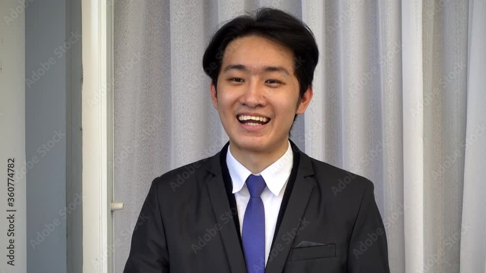 Happy Asian young handsome businessman wear a suit work from home he is video call conferences to explain or present job with the team Happy Asian young handsome businessman wear a suit work from home he is video call conferences to explain or present job with the team