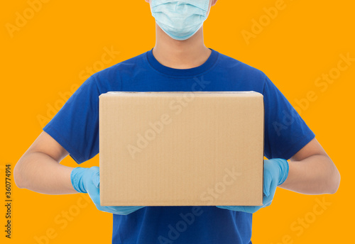 Delivery man hand in medical gloves and wearing mask holding cardboard box mockup template, Delivery service concept.