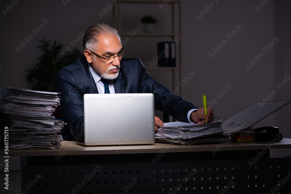Old male employee working late at workplace Old male employee working late at workplace