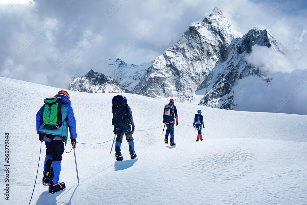 Group of climbers with backpacks on the glacier. Success, freedom and happiness, achievement in mountains. Climbing sport concept.