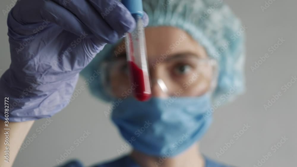 Closeup of microbiologist or medical worker hand with blue surgical gloves looking blood test result as positive for the new rapidly spreading Coronavirus. pandemic and epidemic COVID.