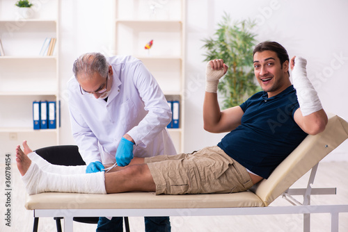 Young injured man visiting old doctor traumatologist