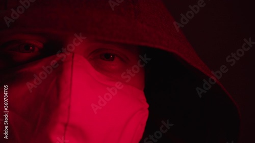 A man in a hood and a close-up mask symbolizes the pandemic in the world 