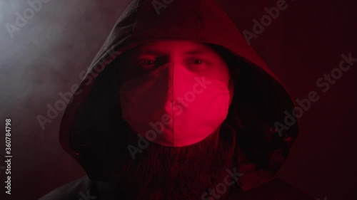 A man in a protective mask and hood looks directly at the camera amid the smoke. High quality 4k footage