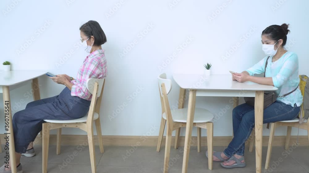 two asian women wearing face mask and keeping social distancing in the restaurant during covid-19 or coronavirus outbreak. new trend concept two asian women wearing face mask and keeping social distancing in the restaurant during covid-19 or coronavirus outbreak. new trend concept