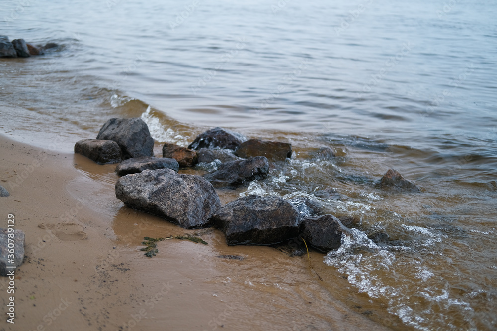 Beach with stones, yellow sands, river waves