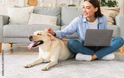 Young woman at home with laptop and happy dog photo