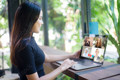 Young Woman is looking at her computer screen while business meeting through video conferencing application