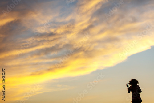 Silhouette of a curly-haired girl against the background of the sunset