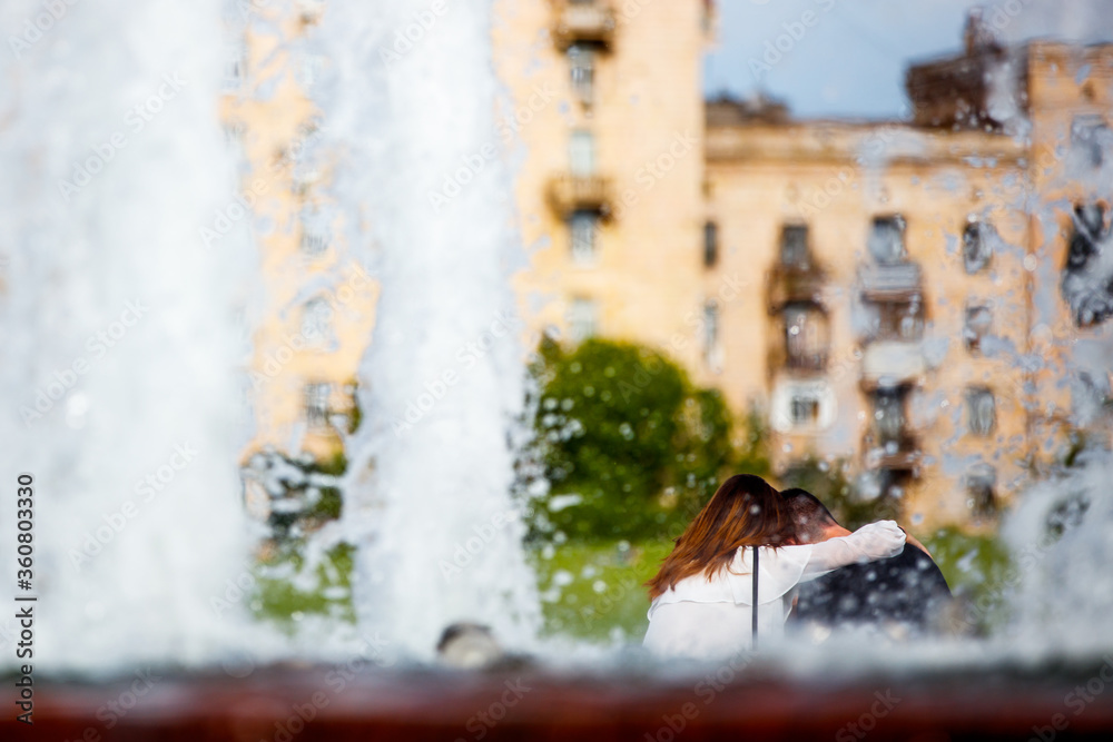 Fototapeta premium Couple relaxing near the fountain on a summer day