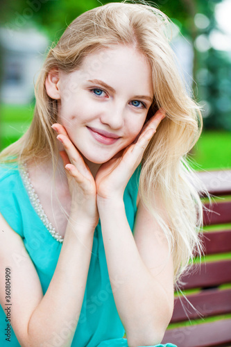 Portrait of a young blonde girl in a turquoise dress