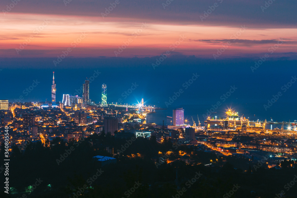 Naklejka premium Batumi, Adjara, Georgia. Aerial View Of Urban Cityscape At Sunset. Town At Evening Blue Hour time. City In Night Lights Illuminations