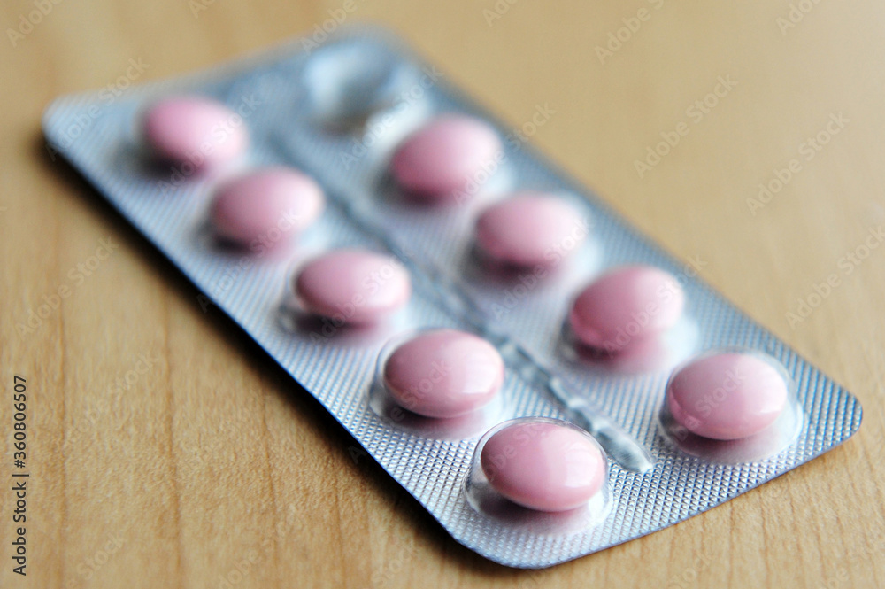Sachet of pink pills on a wooden surface Sachet of pink pills on a wooden surface