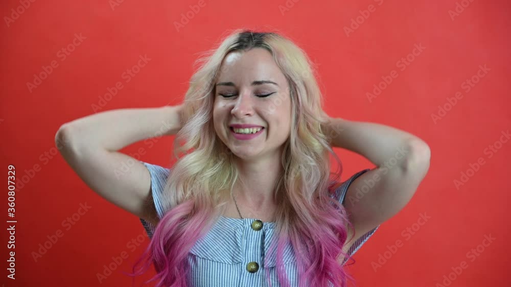 Cute caucasian cheerful woman on a red background. Close up of a happy woman with colored hair smiling at the camera. Studio portrait smiling girl. Cute caucasian cheerful woman on a red background. Close up of a happy woman with colored hair smiling at the camera. Studio portrait smiling girl.