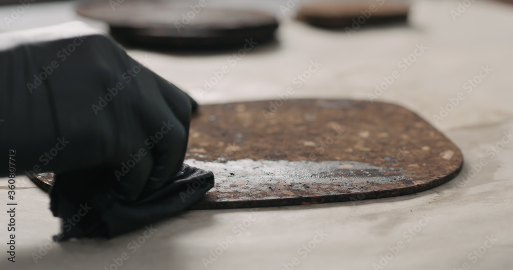 man hands applying oil finish on dark cork mat