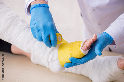 Young leg injured woman visiting old doctor traumatologist photo