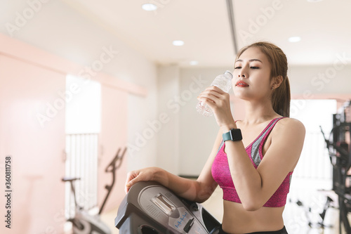 Fitness woman exercise in the gym and drinking water from bottle.
