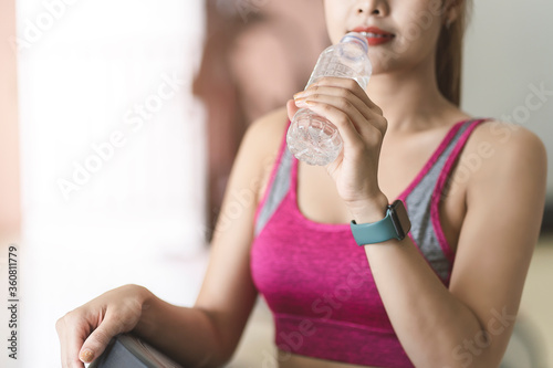 Fitness woman exercise in the gym and drinking water from bottle.