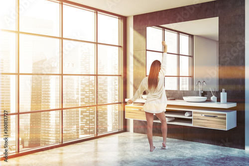 Woman in white and gray bathroom with double sink