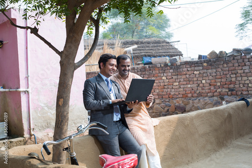 Canvas Print Real estate agent showing online content on laptop to rural farmer