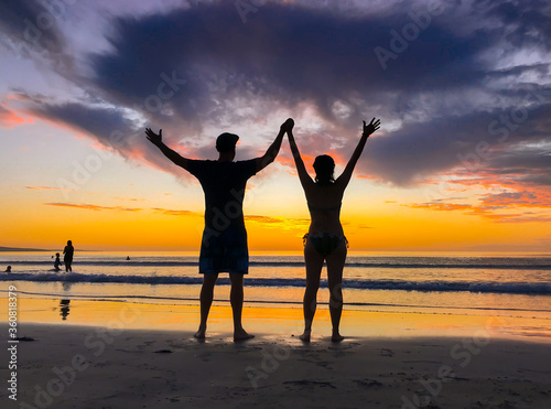 Silhouettes of couple in love at beach sunset celebrating freedom and love