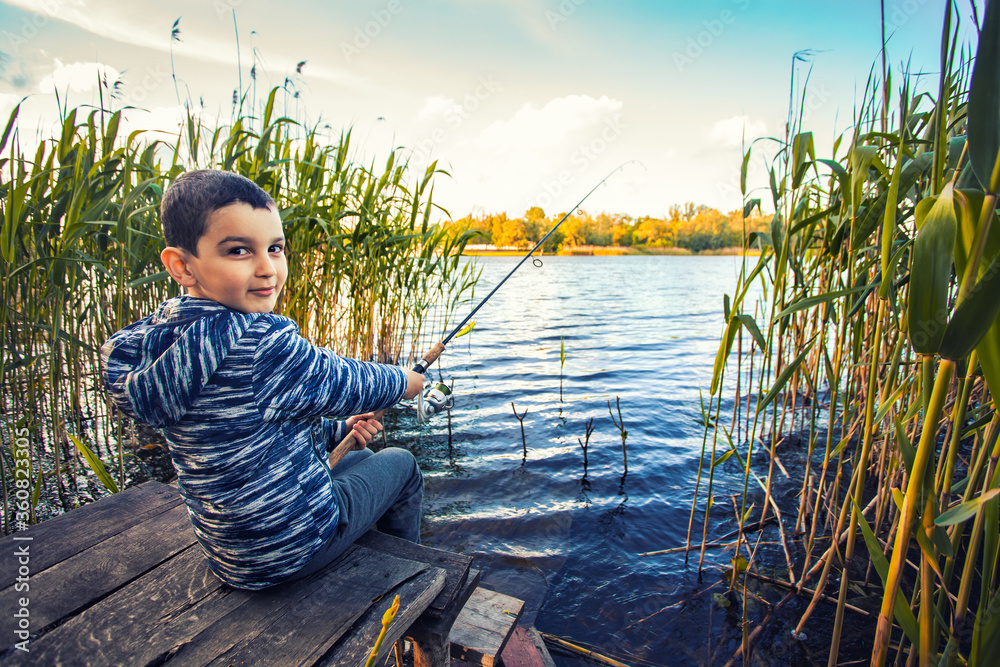 Cute boy catches fish on a summer lake. Activity in nature fishing. Happy childhood Cute boy catches fish on a summer lake. Activity in nature fishing. Happy childhood