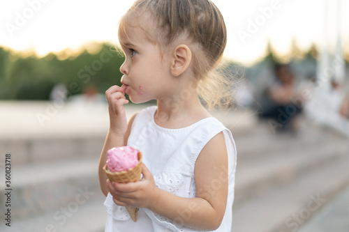Little caucasian girl 3 years old eats ice cream closeup portrait