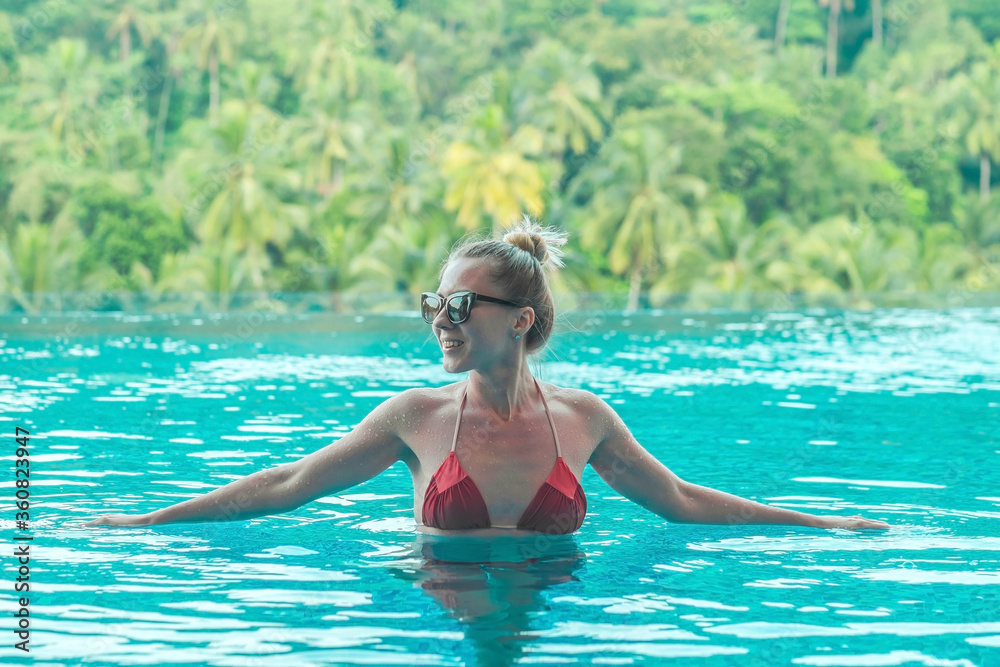 Happiness woman traveler in bikini in water pool near sea coastline