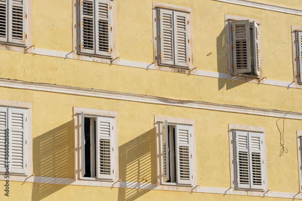 Traditional Mediterranean style building with white shutters on yellow wall