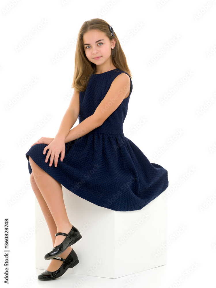 Portrait of a cute girl sitting on a white cube hands on her knees Portrait of a cute girl sitting on a white cube hands on her knees