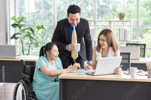 Asian disabled businesswoman working with the colleague, meeting and consulting feeling happy, smiling and enjoy, working together in the workplace